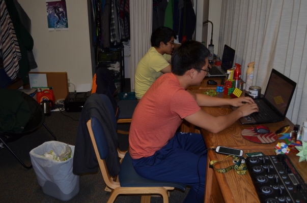 Jeremy Chen works on his computer late at night, while his roommates sit next to him and play League of Legends.  His desk almost looks ready to fit right in at google.